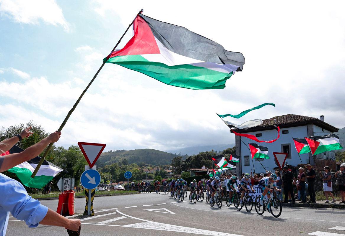 Cycling - Vuelta a Espana - Stage 13 - Cabezon de la Sal to L'angliru - Cantabria, Spain - September 5, 2025 Riders pass protesters with Palestine flags during stage 13 - REUTERSPIX