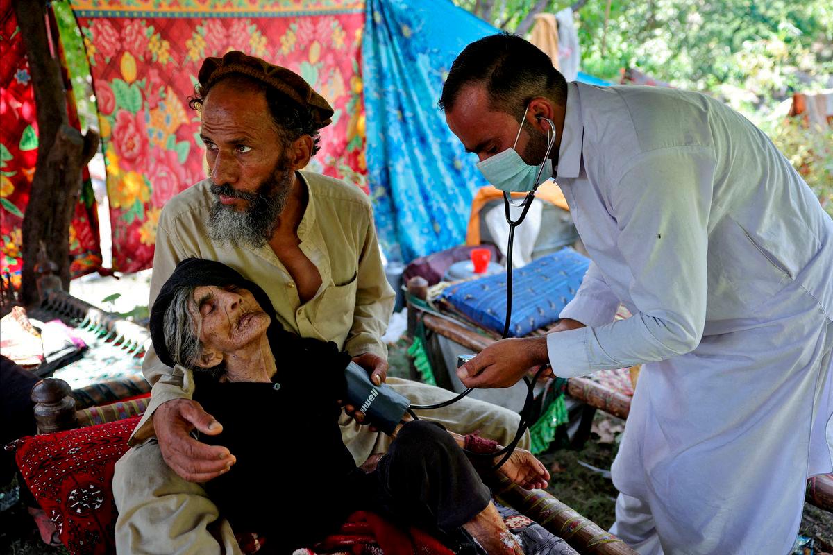 Nazar Shah, 43, holds on to his mother, as Dr Hazrat Gul checks Rad Bibi, an injured Afghan woman who claims to be 110-years-old, outside her damaged house, following a deadly earthquake that struck Afghanistan’s Kunar and Nangarhar provinces, in Nurgal district, Kunar province, Afghanistan, September 4, 2025. REUTERS/Sayed Hassib TPX IMAGES OF THE DAY