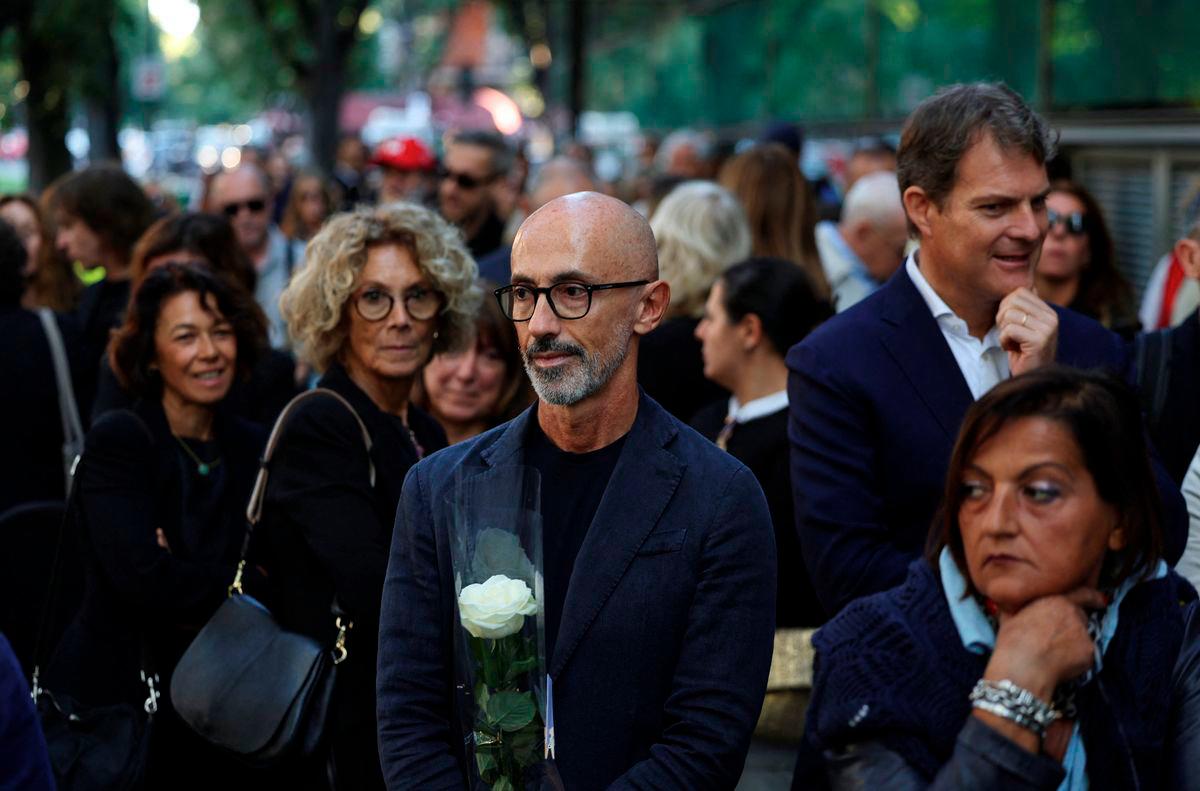 A man holding a rose looks on while people queue outside the Armani/Teatro to pay tribute to designer Giorgio Armani, following his death at the age of 91, in Milan, Italy September 6, 2025. - REUTERS