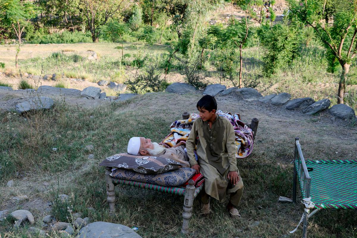 Seorang budak lelaki duduk di sebelah datuknya di atas katil di luar rumah mereka, susulan gempa bumi dahsyat di kampung Bambakot, daerah Dera Noor, wilayah Nangarhar, Afghanistan, 6 September 2025. REUTERS/Sayed Hassib