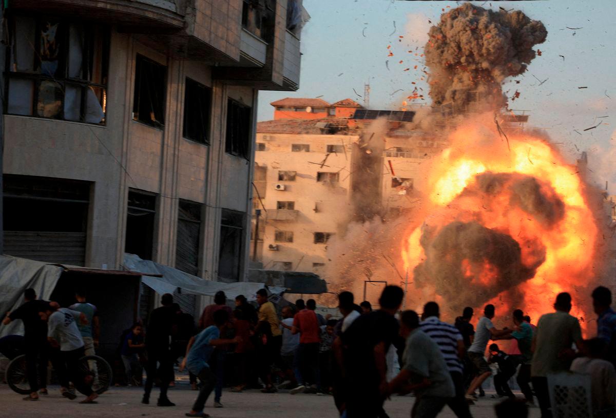 Palestinians react, as smoke and flames rise while a residential building collapses after an Israeli air strike, in Gaza City, September 7, 2025. - REUTERS