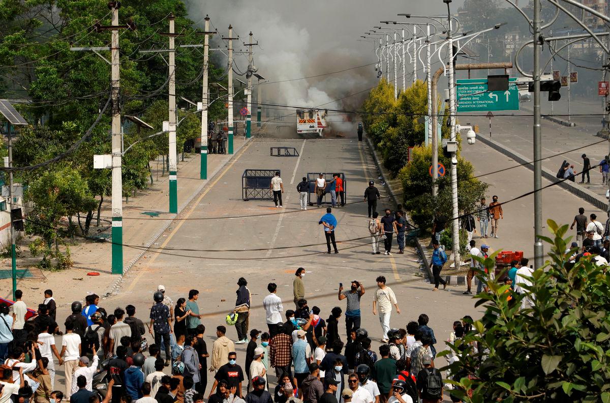 Smoke billows from an ambulance next to riot police officers and demonstrators during a protest against corruption and the government’s decision to block several social media platforms, in Kathmandu, Nepal September 8, 2025. REUTERS/Stringer