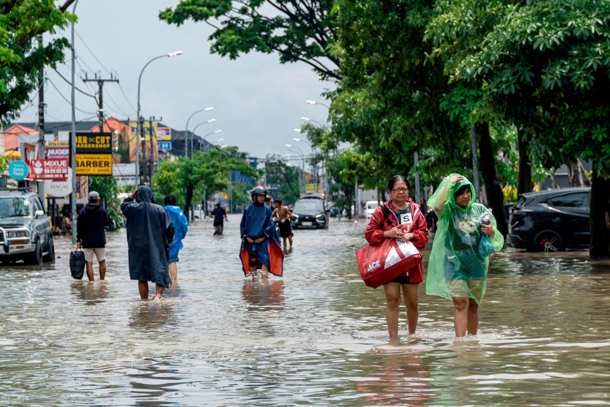 FILE PHOTO: People carrying their belongings wade through a flooded street following overnight heavy rains in Legian, Badung, Bali, Indonesia September 10, 2025. REUTERS/Dicky Bisinglasi/File Photo