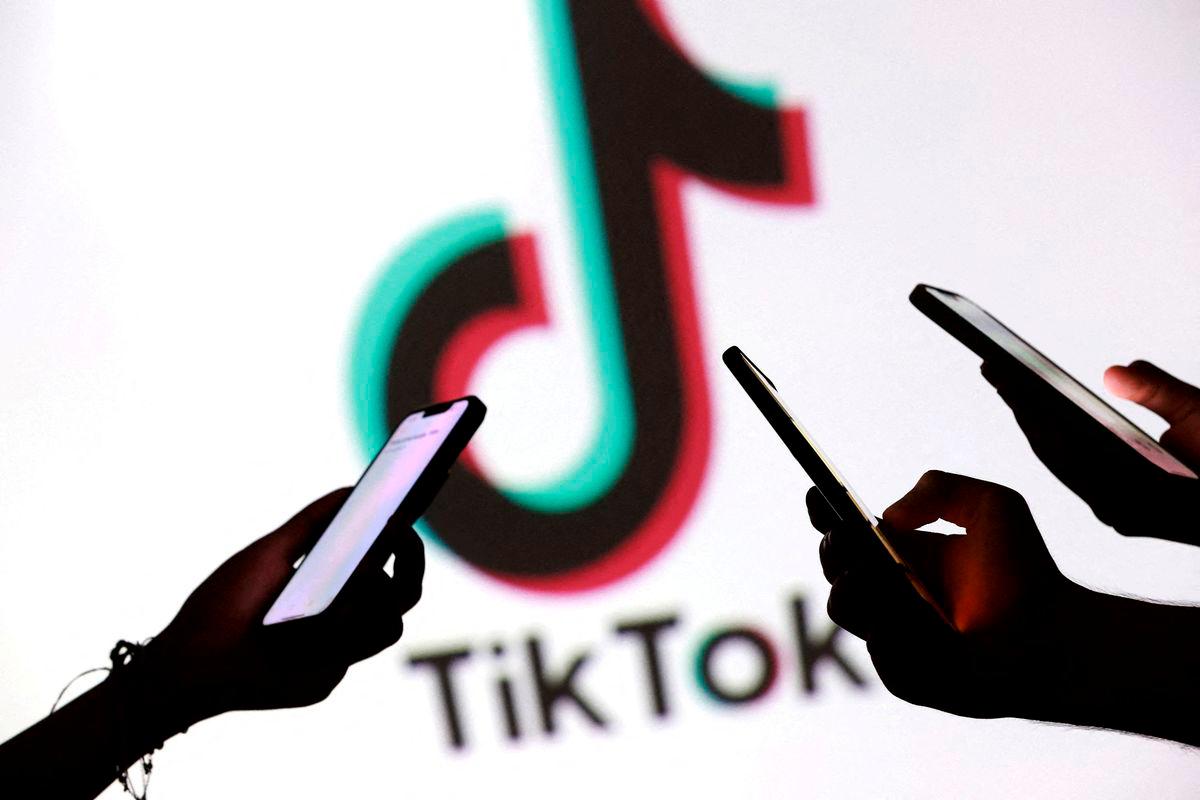 FILE PHOTO: Teenagers pose for a photo while holding smartphones in front of a TikTok logo in this illustration taken September 11, 2025. REUTERS/Dado Ruvic/Illustration/File Photo