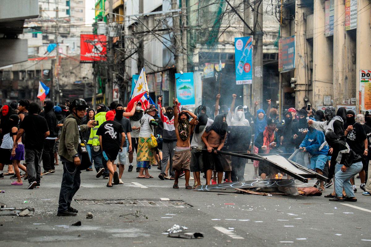 Smoke rises from burning objects as demonstrators show their middle fingers and shout towards police officers during a protest denouncing what they say is corruption linked to flood control projects, in Manila, Philippines, September 21, 2025. REUTERS/Lisa Marie David