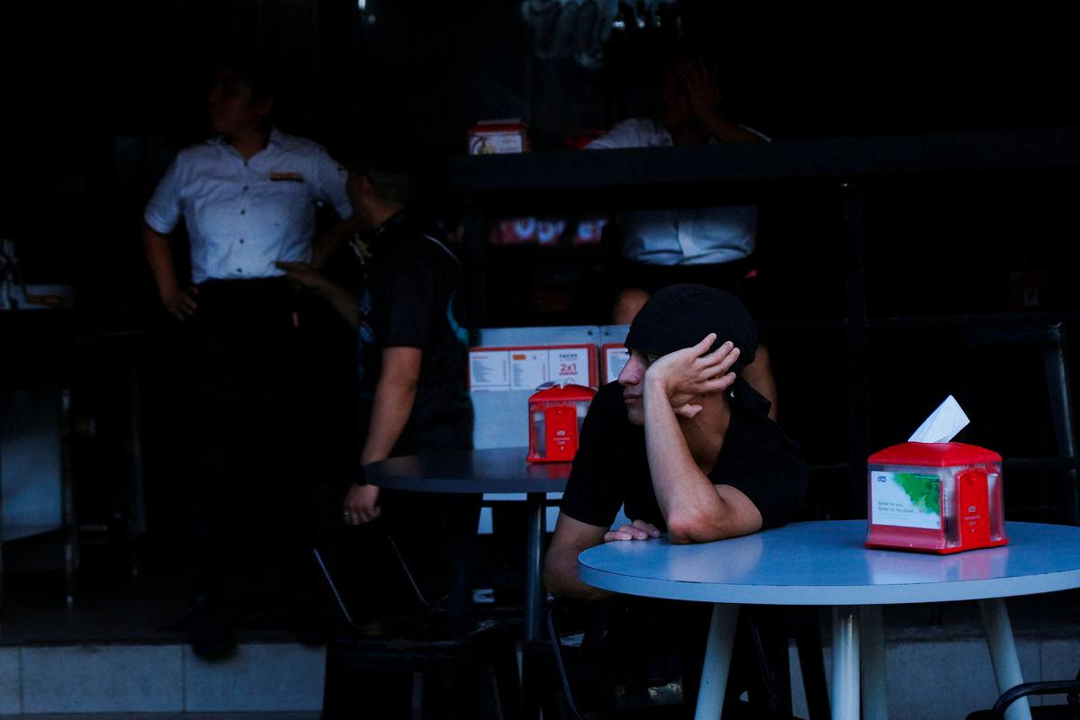 A tourist sits at a bar during a power grid collapse that caused a blackout across three states in southeastern Mexico, in Cancun, Mexico, September 26, 2025. - REUTERSPIX