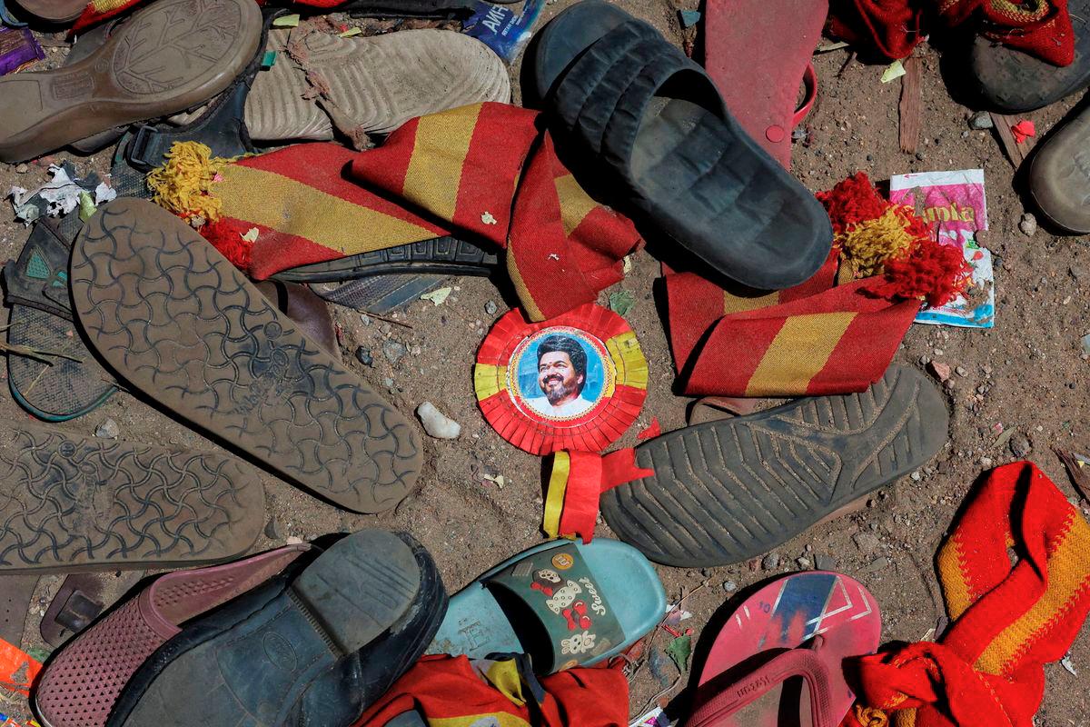A badge with picture of Vijay, actor and politician, lies amid footwears and other belongings left by attendees at the site of a stampede incident during an election campaign rally held by Tamilaga Vettri Kazhagam party, in Karur district of Tamil Nadu, India, September 28, 2025. - REUTERS