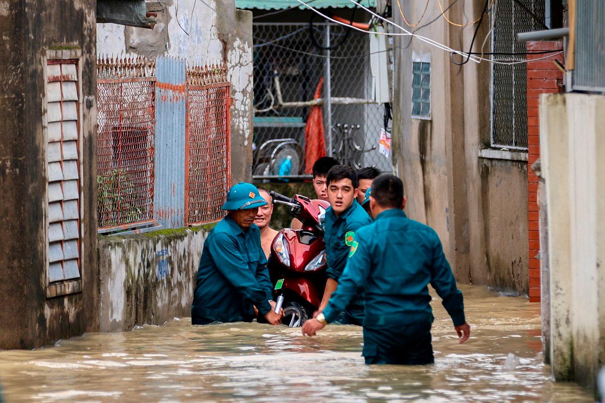 Paramilitary officers carry a motorcycle from a flooded area after Typhoon Bualoi made landfall in Nghe An province, Vietnam. - REUTERS/Thinh Nguyen