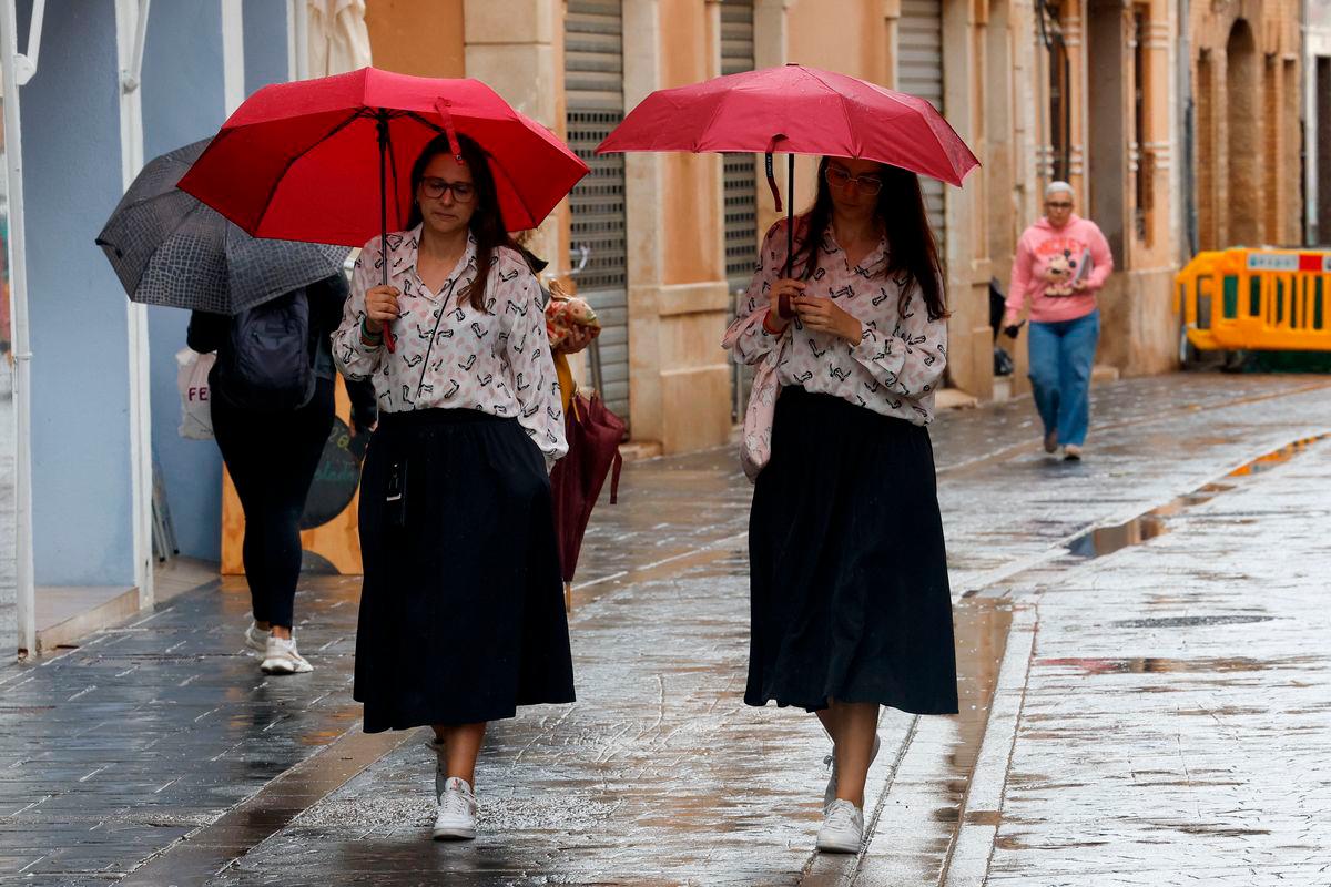 People hold umbrellas as it rains in Paiporta, near Valencia, Spain September 30, 2025. REUTERS/Eva Manez