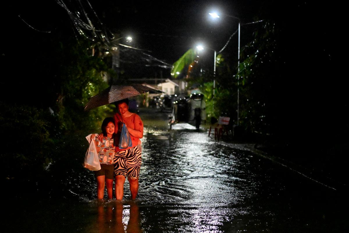 People wade through a flooded street following rain, intensified by Severe Tropical Storm Matmo, in Santa Lucia, Calumpit, Bulacan province, Philippines, October 3, 2025. - REUTERSPIX
