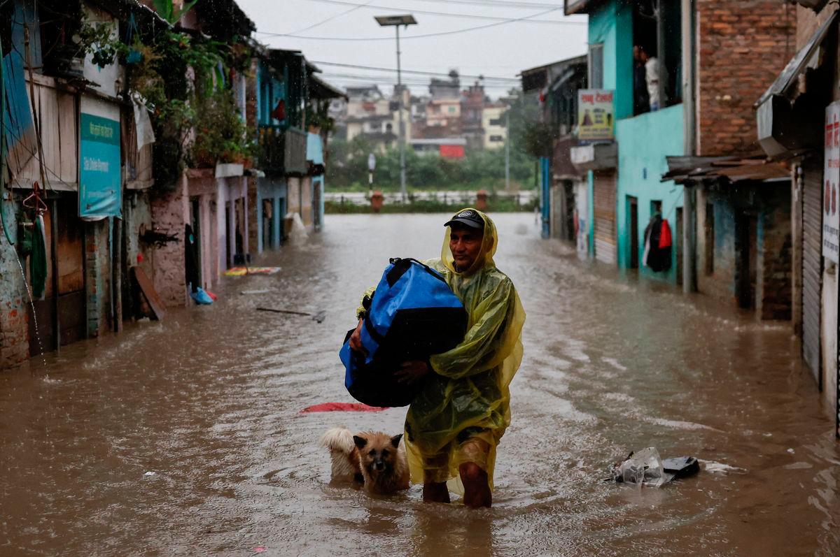 A man carries a bag as he wades through a flooded street along the bank of overflowing Bagmati River following heavy rains, in Kathmandu, Nepal, October 4, 2025. REUTERS/Navesh Chitrakar