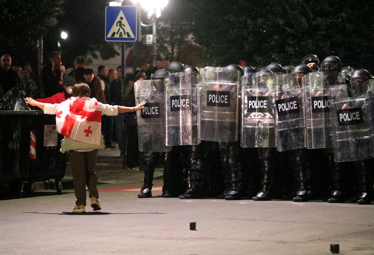 A protester wearing a Georgian flag walks towards police officers blocking the street during an opposition rally on the day of local elections in Tbilisi, Georgia October 4, 2025. REUTERS/Irakli Gedenidze