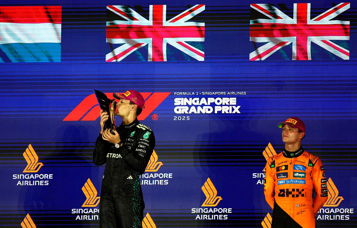 George Russell celebrates on the podium with the trophy after winning the Singapore Grand Prix with third placed McLaren’s Lando Norris. - REUTERS/Edgar Su