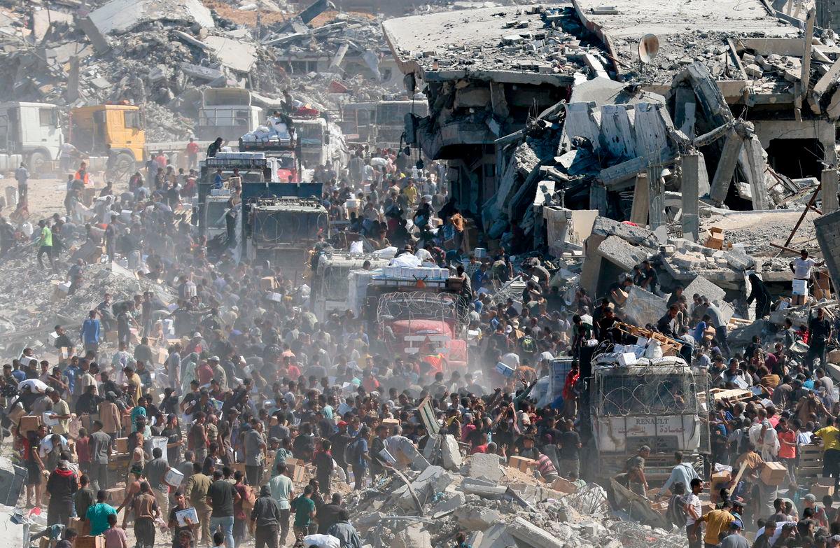 Palestinians collect aid supplies from trucks that entered Gaza, amid a ceasefire between Israel and Hamas, in Khan Younis, in the southern Gaza Strip October 12, 2025. REUTERS/Ramadan Abed