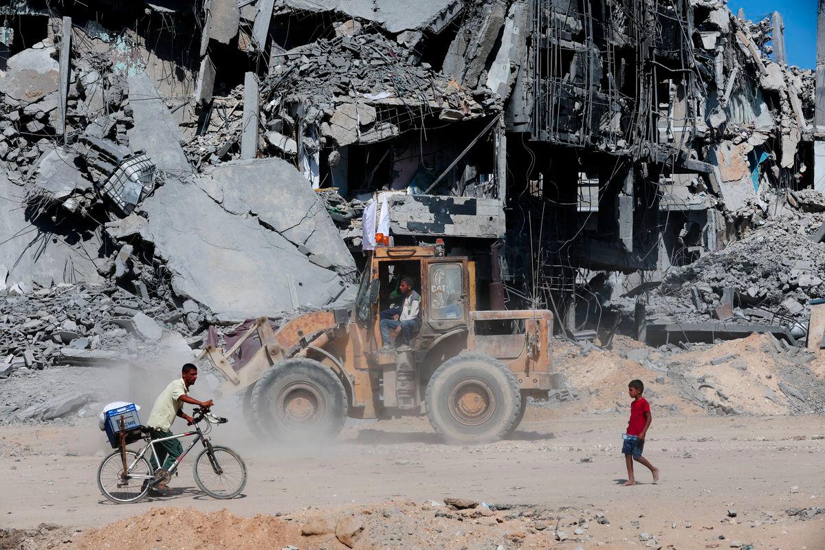 Rakyat Palestin melintasi runtuhan, ketika gencatan senjata antara Israel dan Hamas di Gaza, di Khan Younis, selatan Semenanjung Gaza, pada 14 Oktober 2025 - Reuters
