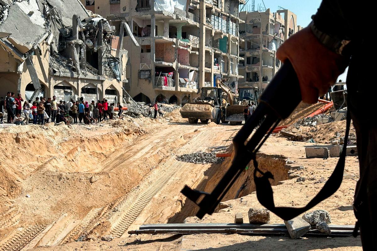 Hamas militant stands guard, as heavy machinery operates at the site where searches are underway for the bodies of hostages killed after being seized by Hamas during the October 7, 2023 attack, amid a ceasefire between Israel and Hamas, in Khan Younis, southern Gaza Strip, October 17, 2025. - REUTERSPIX