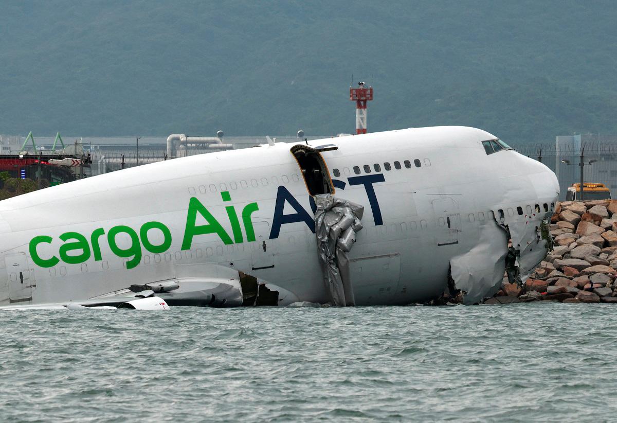 A cargo plane lies partially in the sea after veering off the runway during landing at Hong Kong International Airport in Hong Kong, China, October 20, 2025. - REUTERS/Tyrone Siu