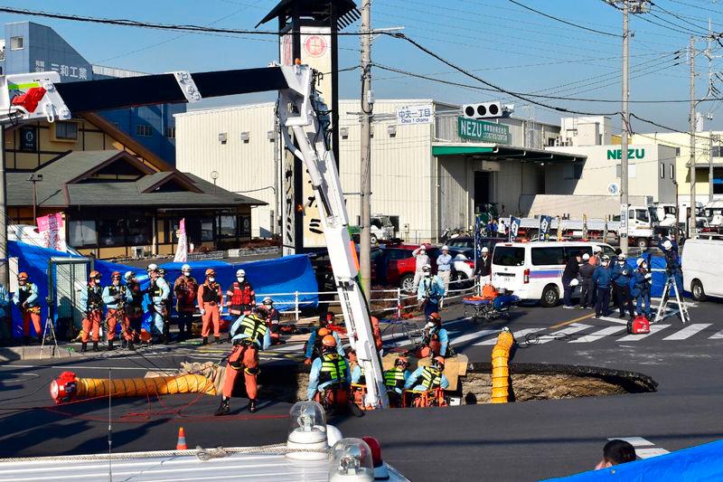 Firefighters work to rescue a truck driver after his vehicle was swallowed up by a sinkhole at a prefectural road intersection, in the city of Yashio, Saitama Prefecture - AFPpix