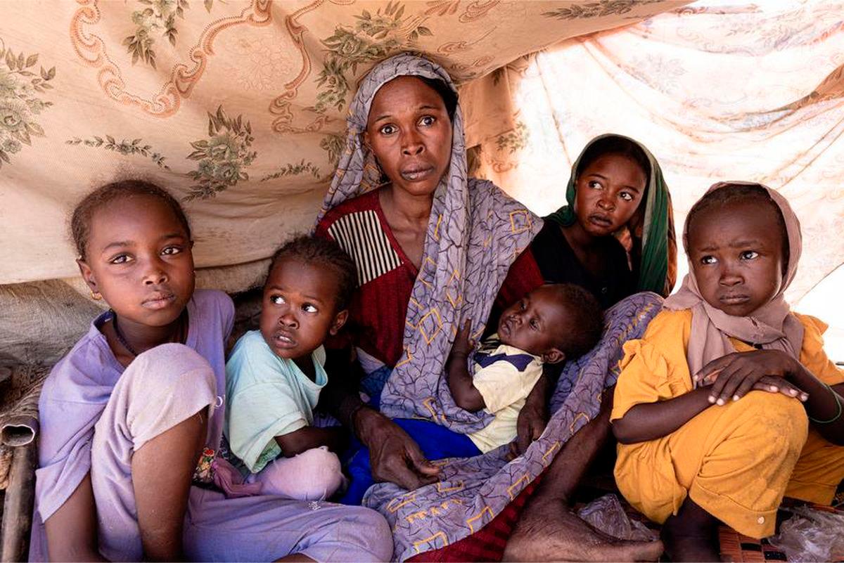 A displaced woman and some children sit under a tent built from logs and cloth in Tawila, North Darfur, Sudan, Aug. 8, 2025. (The UN World Food Programme/Handout via Xinhua)