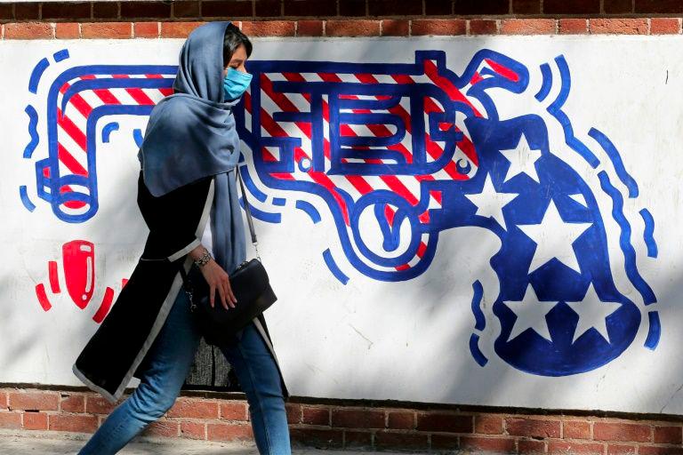 An Iranian woman walks past a mural painted on the outer walls of the former US embassy in Tehran on Sept 20, 2020. — AFP