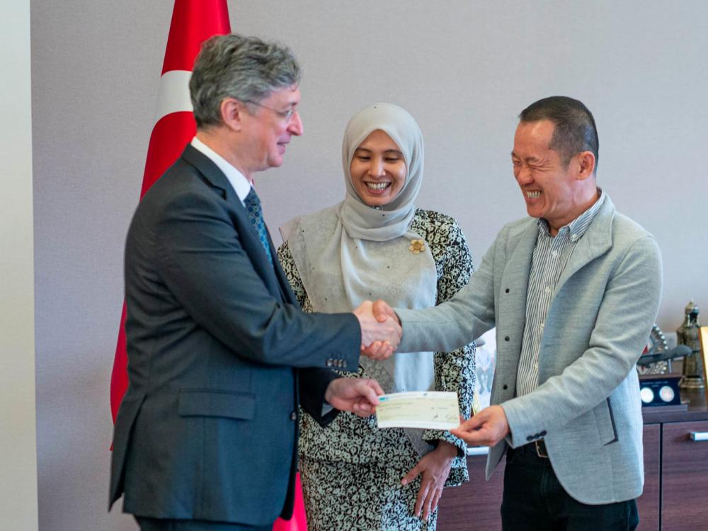 Lee (right) presents the cheque for RM1 million to Emir while Nurul looks on. - Picture from Nurul Izzah/Facebook