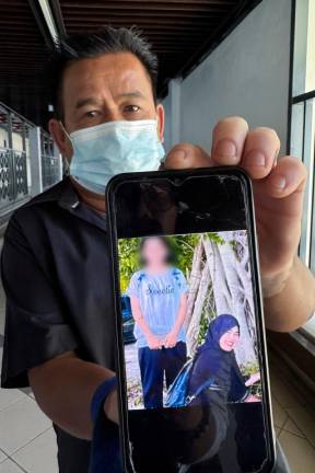 Bismi Che Hin, 60, shows a photo of her sister Suriya, 51, and her niece, Nur Afrina Alisha Abdul Rahim, 11, who were found dead and are believed to have been murdered. - BERNAMApix