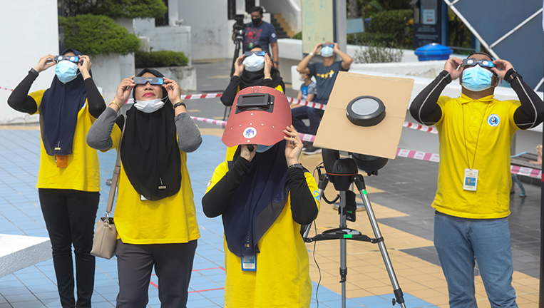$!THRILLED SKYWATCHERS ... Planetarium Negara staff using protective glasses to view the partial solar eclipse in Kuala Lumpur yesterday. – ASYRAF RASID/THESUN