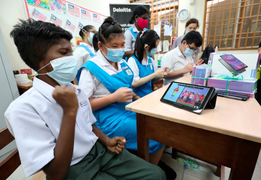 $!COOL GADGET ... Students Muhamad Fitri Abdullah, 13, and Chow Lay Ching, 15, from a special-needs school in Kuala Lumpur watching a video on a tablet presented by the YTL Foundation during an education event yesterday. – MASRY CHE ANI/THESUN
