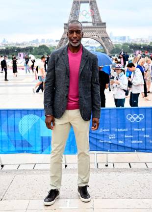 Former athlete Michael Johnson of United States poses for a photo in front of the Eiffel Tower as he arrives for the opening ceremony. REUTERS