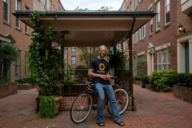 Tarek Maassarani, who adopts a low consumption and carbon footprint lifestyle, poses for a photo with his bicycle with a frame that is over a decade old, at his friend’s apartment complex’s garage in Washington. — AFP