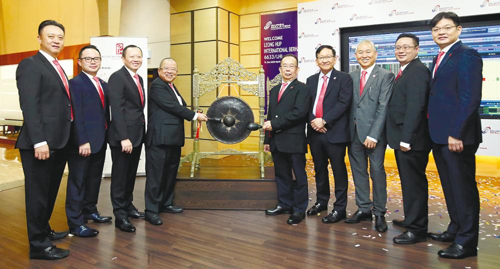 Francis Lau (left) and Leong Hup executive chairman Lau Chia Nguang hit the gong at the listing ceremony, witnessed by other directors of the company.