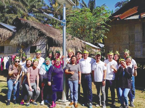 Asmah Pejajah, community leader of the Orang Asli village (middle) standing next to Sukanto and the Signify team in front of the solar lighting installed by Signify at the residential areas.