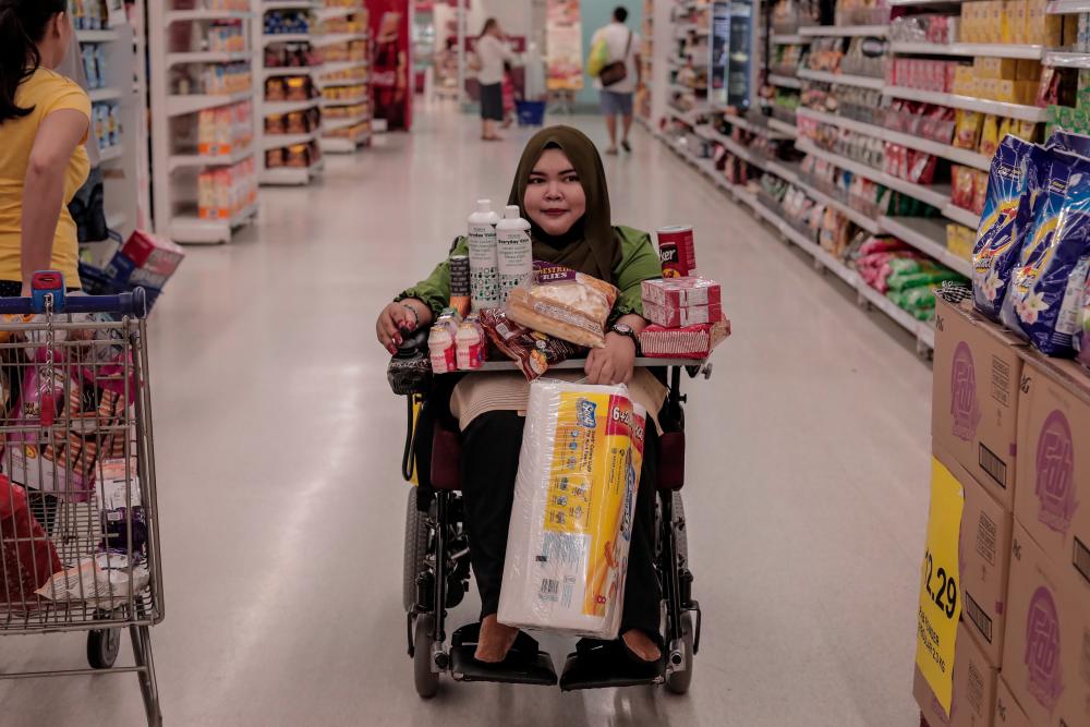 $!Navigating her motorised wheelchair though the many aisles, Nur Fazira shops for groceries and business supplies.