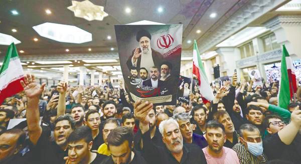 Mourners hold posters of Raisi during a funeral ceremony for him. – AFPpix