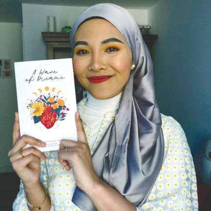 Kamalia posing with her second book, A Wave of Dreams. — Photo Courtesy of Kamalia Hasni.