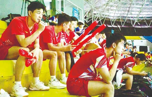 Chinese badminton players watching from the stands as medics attend to Zhang. – AFPPIX