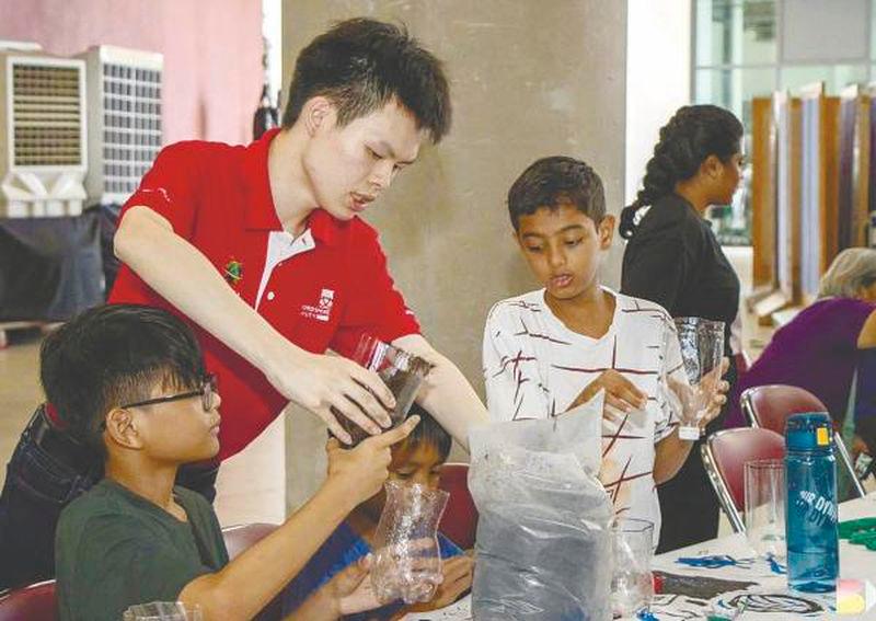 University student assisting the refugee children to create terrariums using recycled materials.