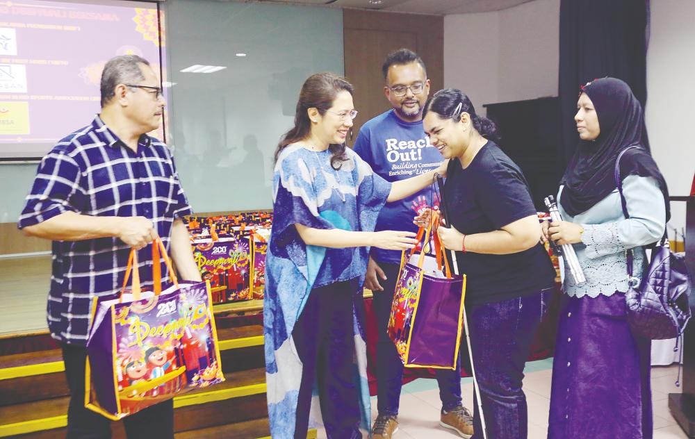 Sunita handing out gift bags to visually impaired beneficiaries at the Malaysian Association for the Blind multipurpose hall in Brickfields, Kuala Lumpur yesterday. – AMIRUL SYAFIQ/THESUN