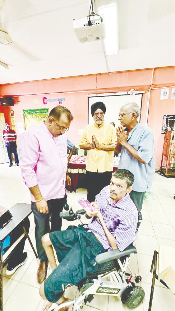 A recipient accepting cash aid presented by Sentosa assemblyman Dr G. Gunarajah (left) and HCIC chairman Mejar Singh Katar Singh at a simple ceremony recently. – Pic courtesy of Hamidi’s Comrades in Charity