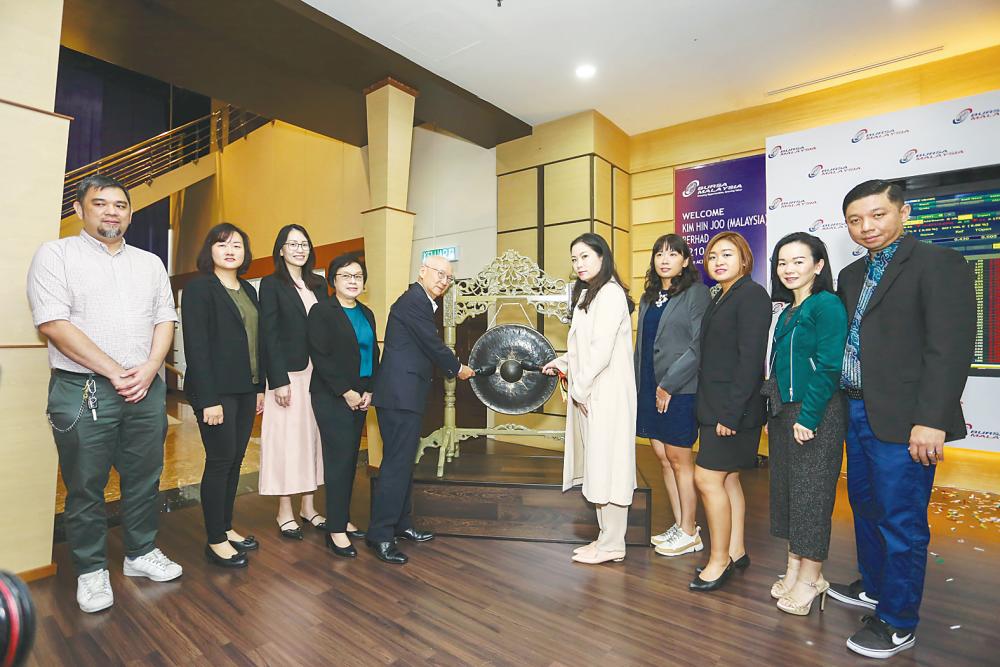 Pang (fifth from left) and managing director Pang Shu Ming hitting the gong at the listing ceremony yesterday, witnessed by CFO Sammi Phuan Siew Ling (second from left), directors Kor Yann Ning and Goh Poh Teng (third and fourth from left, respectively) as well as other senior management staff.