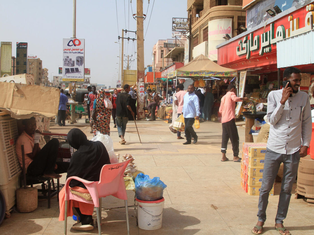 Sudanese walk past shops in Khartoum’s twin city Omdurman on July 29, 2025. - AFP