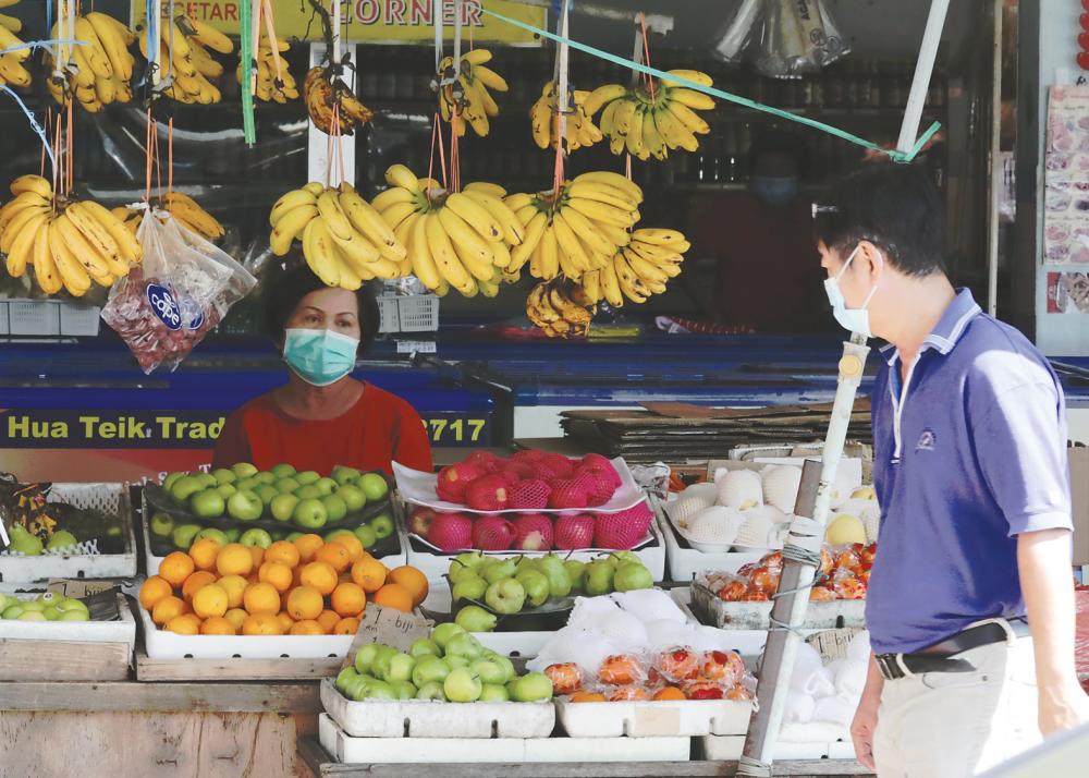 $!Fruit seller Wendy Mei waits for customers at her stall in Jalan Pasar, Bukit Mertajam yesterday. Petty traders like Mei, who are not under the government support structure, also need government support to ensure they do not fall by the wayside due to the impact of the Covid-19 pandemic on the economy. – MASRY CHE ANI/THESUN