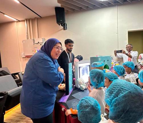 Children observing x-ray images to learn about the importance of diagnostic imaging in healthcare at the radiology station.