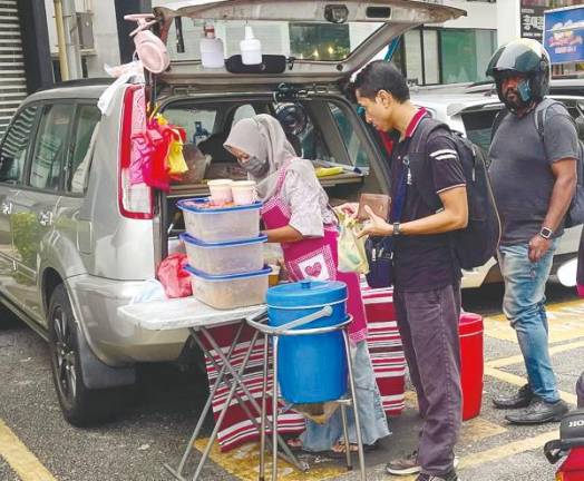 A trader selling food from an open car boot near the main road in Taman Tun Dr Ismail. – ADIB RAWI YAHYA/THESUN