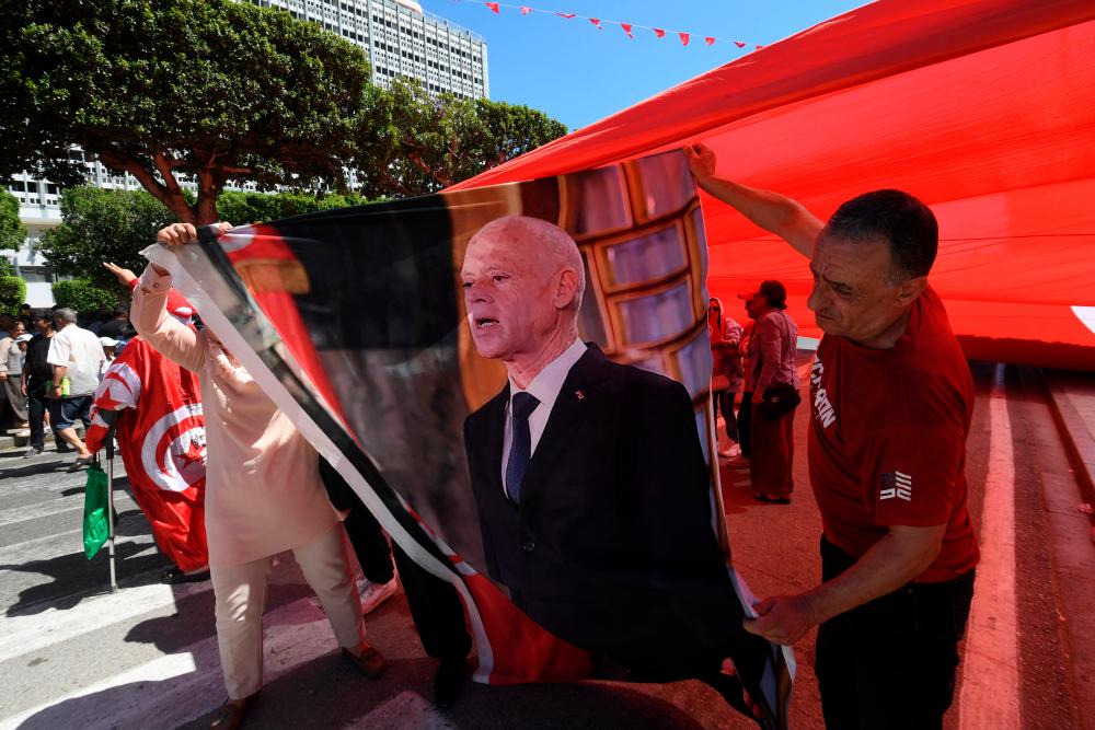 Backing for the President: Supporters of Tunisian President Kais Saied hold his image during a rally in Tunis, on July 25, 2024, as the nation celebrates the 67th anniversary of foundation of the republic. (Photo by Fethi Belaid / AFP)