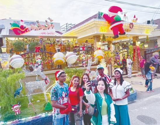 Visitors pose with house owner Charles Dorney (wearing cap), his wife Christe Samasundram (right) and son Dohnaven. – MASRY CHE ANI/THESUN