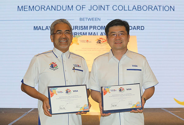 Ng (right) and Musa posing after the MoU signing between Visa and Tourism Malaysia in Kuala Lumpur yesterday.