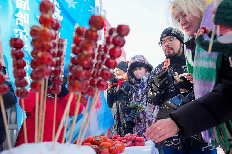 $!Foreign tourists purchasing candied hawthorn on a stick.(Xinhua)