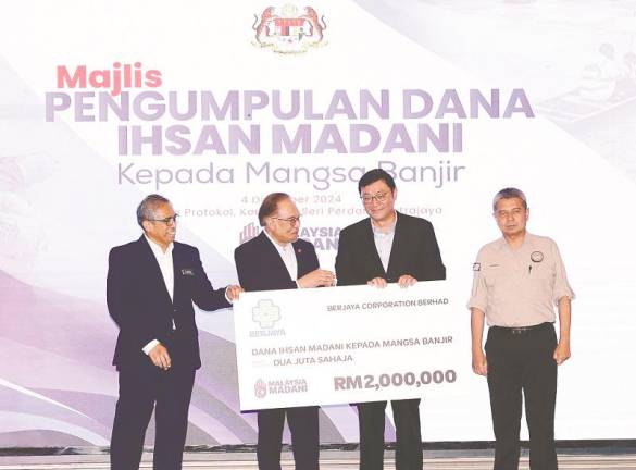 Anwar receiving the contribution from Tan during a simple ceremony yesterday.