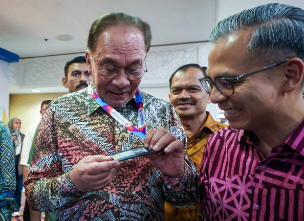 Prime Minister Datuk Seri Anwar Ibrahim looks at the media pass presented by Communications Minister Datuk Fahmi Fadzil while attending the HAWANA 2025 Summit at the Kuala Lumpur World Trade Centre (WTCKL) today.